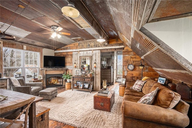 15335 Hh Hwy, Platte City, MO 64079 - living area featuring wooden walls, vaulted ceiling, wood finished floors, a ceiling fan, and a glass covered fireplace