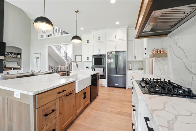 8422 NE 147th St, Liberty, MO 64068 - kitchen featuring black appliances, wall chimney range hood, light wood-style flooring, light stone countertops, and recessed lighting