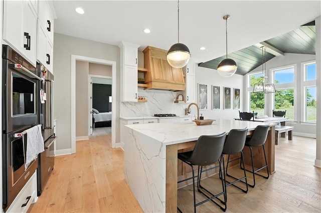 8422 NE 147th St, Liberty, MO 64068 - kitchen with open shelves, custom range hood, light wood-style floors, stainless steel double oven, and gas cooktop