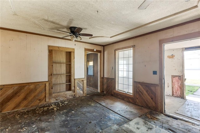 715 Walnut Ave, Osawatomie, KS 66064 - entrance foyer featuring plenty of natural light, wood walls, a ceiling fan, a textured ceiling, and crown molding