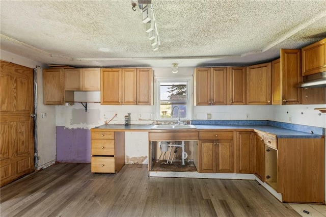 715 Walnut Ave, Osawatomie, KS 66064 - kitchen featuring wood finished floors, brown cabinetry, under cabinet range hood, and a textured ceiling