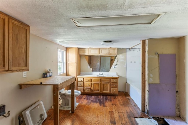 715 Walnut Ave, Osawatomie, KS 66064 - kitchen with dark wood finished floors, a textured ceiling, brown cabinetry, and light countertops