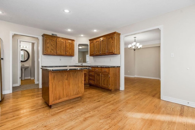 1129 SW Georgetown Dr, Lees Summit, MO 64082 - kitchen with dark countertops, a chandelier, a kitchen island, light wood-style floors, and recessed lighting