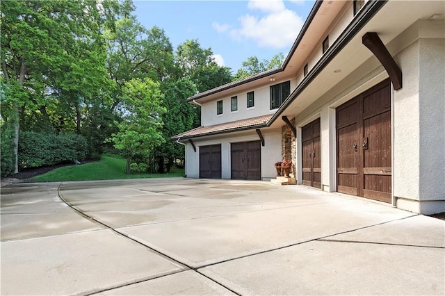 11110 W 146th Ter, Overland Park, KS 66221 - view of side of home with stucco siding, a garage, driveway, and stone siding