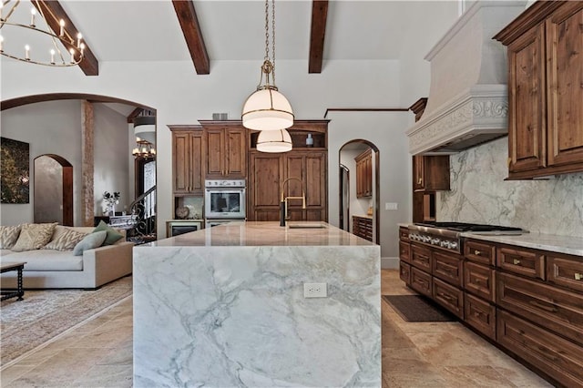 11110 W 146th Ter, Overland Park, KS 66221 - kitchen featuring a chandelier, arched walkways, stainless steel appliances, light stone counters, and backsplash