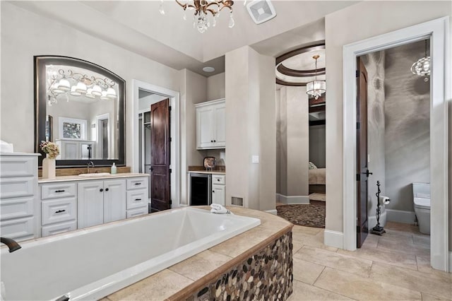 11110 W 146th Ter, Overland Park, KS 66221 - ensuite bathroom featuring a chandelier, beverage cooler, vanity, and a bathtub