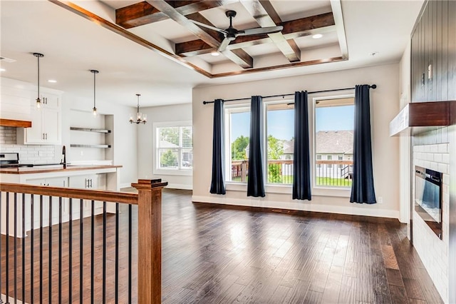 901 NW Hickorywood Dr, Grain Valley, MO 64029 - living room featuring a ceiling fan, a glass covered fireplace, dark wood-type flooring, a chandelier, and beam ceiling