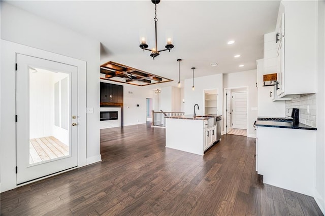 901 NW Hickorywood Dr, Grain Valley, MO 64029 - kitchen with dark countertops, stainless steel dishwasher, a chandelier, dark wood-style floors, and stove