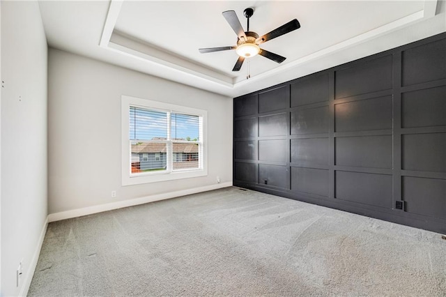 901 NW Hickorywood Dr, Grain Valley, MO 64029 - unfurnished bedroom with carpet flooring, a tray ceiling, a ceiling fan, and a decorative wall
