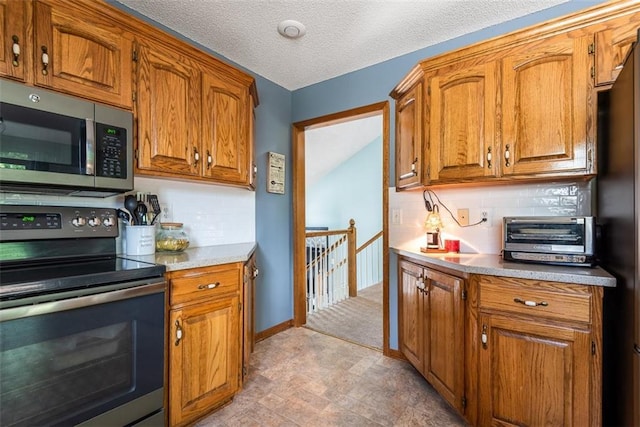 190 W Colleen Ct, Gardner, KS 66030 - kitchen featuring stainless steel appliances, brown cabinetry, tasteful backsplash, light countertops, and a textured ceiling