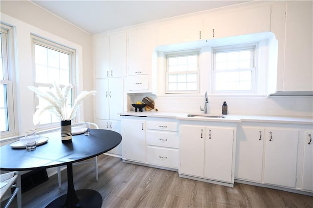 1034 E Lexington Ave, Independence, MO 64050 - kitchen with light countertops, white cabinetry, light wood-style floors, and backsplash