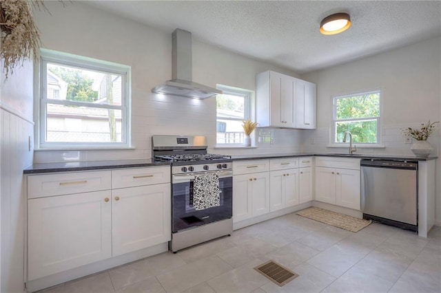 41 S 26th St, Kansas City, KS 66102 - kitchen featuring appliances with stainless steel finishes, wall chimney range hood, plenty of natural light, backsplash, and a textured ceiling