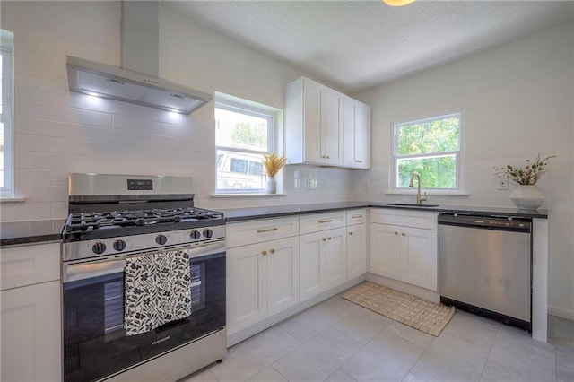 41 S 26th St, Kansas City, KS 66102 - kitchen featuring stainless steel appliances, wall chimney range hood, decorative backsplash, white cabinets, and a textured ceiling
