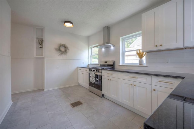 41 S 26th St, Kansas City, KS 66102 - kitchen with stainless steel range with gas stovetop, ventilation hood, white cabinets, decorative backsplash, and a textured ceiling