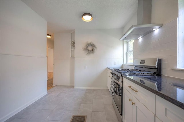 41 S 26th St, Kansas City, KS 66102 - kitchen featuring island exhaust hood, stainless steel range with gas cooktop, dark stone countertops, white cabinets, and a textured ceiling