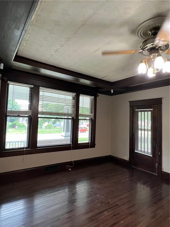 233 Main St, Osawatomie, KS 66064 - empty room with plenty of natural light, dark wood-style flooring, and a ceiling fan