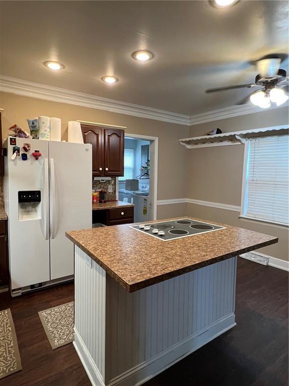 233 Main St, Osawatomie, KS 66064 - kitchen featuring white fridge with ice dispenser, black electric stovetop, ornamental molding, ceiling fan, and dark wood-style floors