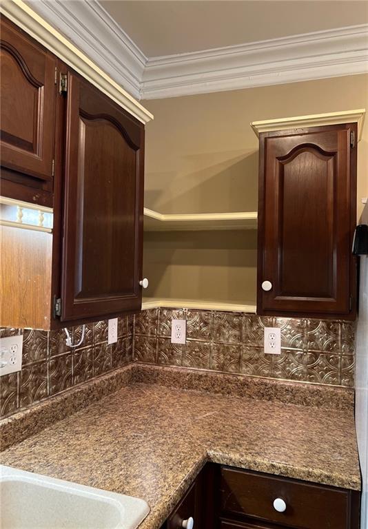 233 Main St, Osawatomie, KS 66064 - kitchen with dark brown cabinetry, ornamental molding, tasteful backsplash, dark countertops, and open shelves