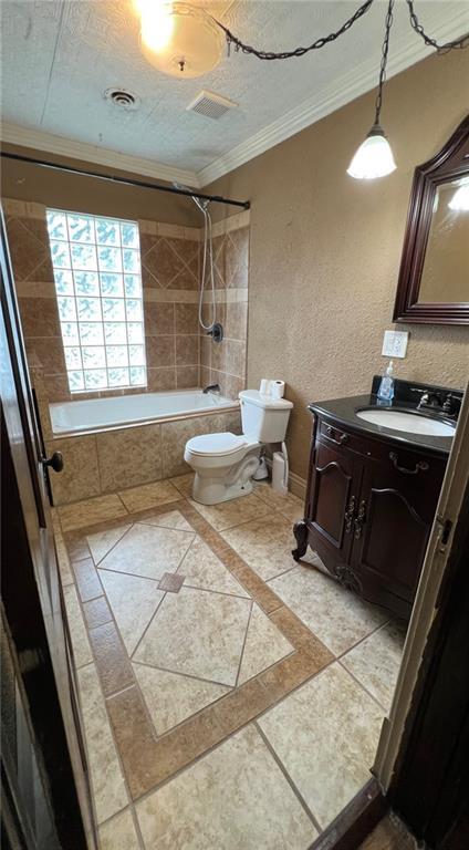 233 Main St, Osawatomie, KS 66064 - bathroom featuring ornamental molding, tiled shower / bath combo, vanity, inlaid floor details, and tile patterned floors