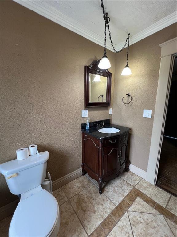 233 Main St, Osawatomie, KS 66064 - bathroom featuring ornamental molding, vanity, tile patterned flooring, and a textured wall