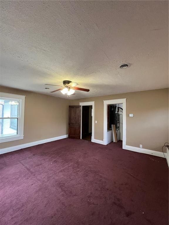 233 Main St, Osawatomie, KS 66064 - unfurnished bedroom featuring a textured ceiling, dark carpet, and a ceiling fan