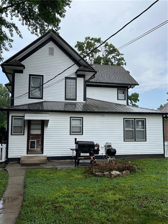 233 Main St, Osawatomie, KS 66064 - rear view of property featuring a yard