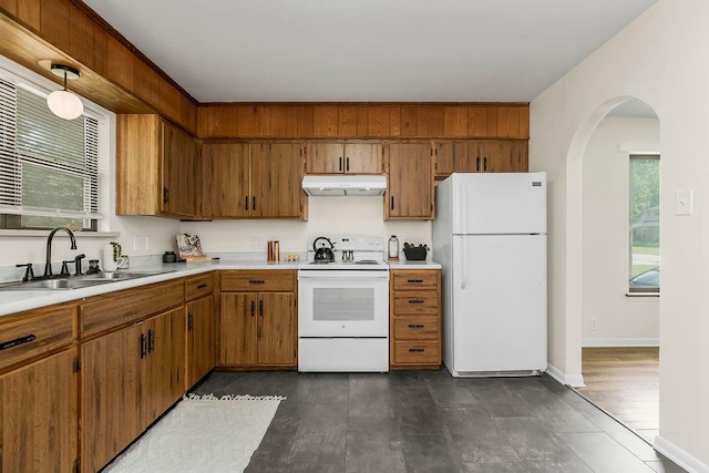 210 S 12th St, Leavenworth, KS 66048 - kitchen with white appliances, under cabinet range hood, arched walkways, light countertops, and brown cabinetry