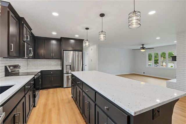 6600 W 93rd Ter, Overland Park, KS 66212 - kitchen featuring appliances with stainless steel finishes, light wood-style floors, a ceiling fan, a center island, and decorative backsplash