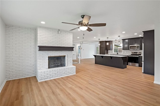 6600 W 93rd Ter, Overland Park, KS 66212 - unfurnished living room featuring a ceiling fan, light wood-type flooring, recessed lighting, and a brick fireplace