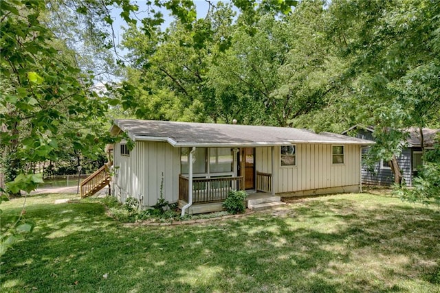 4400 N Brighton Ave, Kansas City, MO 64117 - ranch-style home with covered porch, a front yard, board and batten siding, and stairway