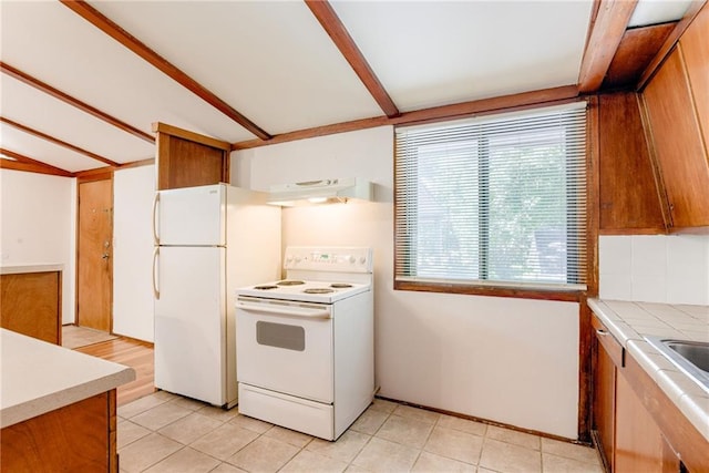 4400 N Brighton Ave, Kansas City, MO 64117 - kitchen with white appliances, under cabinet range hood, brown cabinets, and light tile patterned floors