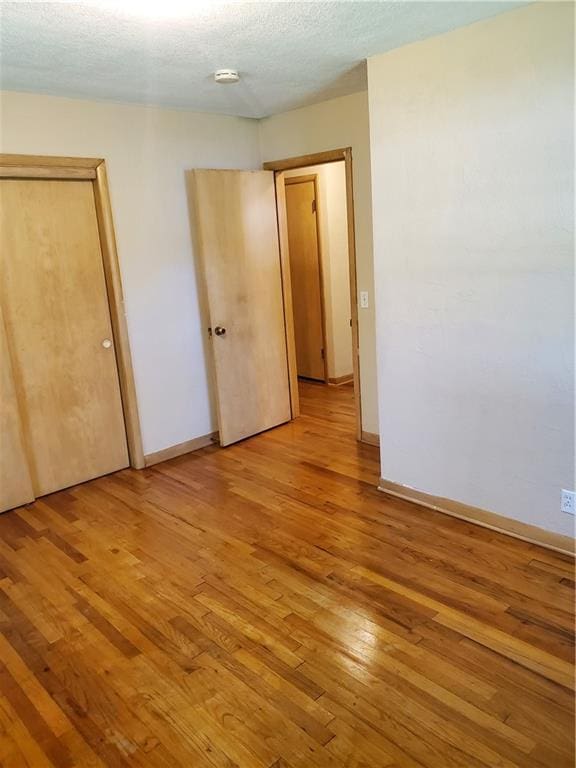 304 Swan St, Lacygne, KS 66040 - unfurnished bedroom with light wood-style floors and a textured ceiling