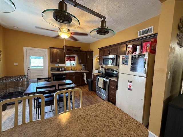 310 W 23rd St, Higginsville, MO 64037 - kitchen with stainless steel appliances, dark brown cabinetry, a ceiling fan, dark wood-style floors, and a textured ceiling