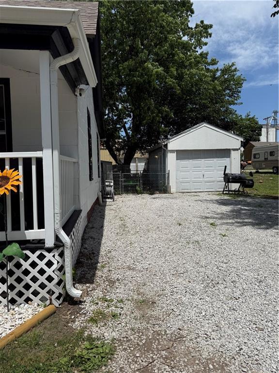 310 W 23rd St, Higginsville, MO 64037 - view of side of home featuring an outdoor structure, gravel driveway, and a detached garage