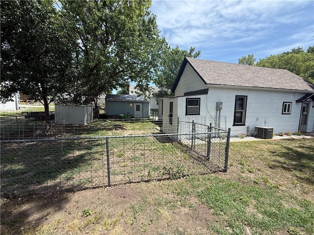 310 W 23rd St, Higginsville, MO 64037 - back of house featuring a shingled roof and a storage unit