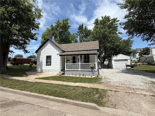 310 W 23rd St, Higginsville, MO 64037 - bungalow-style home with covered porch, a detached garage, an outbuilding, driveway, and a shingled roof