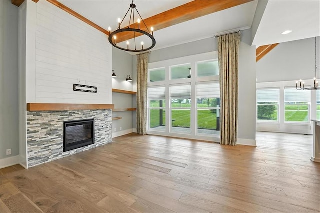 13300 W 174th Pl, Overland Park, KS 66221 - unfurnished living room featuring a chandelier, a towering ceiling, wood-type flooring, and a stone fireplace