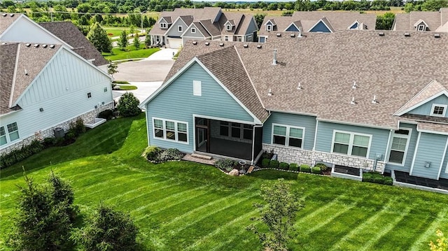 13300 W 174th Pl, Overland Park, KS 66221 - back of property featuring stone siding, a residential view, a lawn, and a sunroom