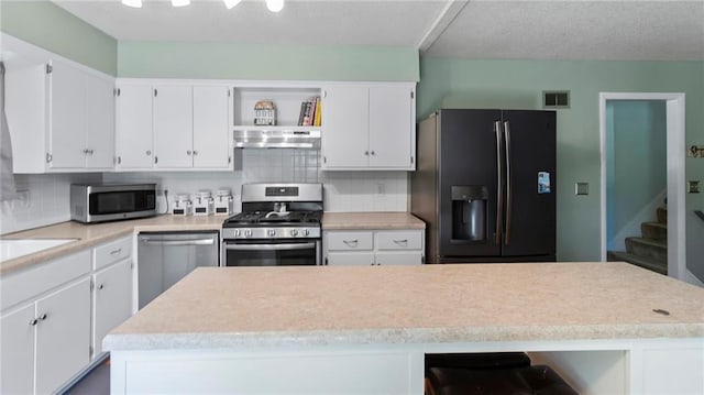 12205 W 67th Ter, Shawnee, KS 66216 - kitchen with stainless steel appliances, under cabinet range hood, open shelves, light countertops, and white cabinets