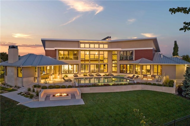 10712 W 165th St, Overland Park, KS 66221 - back of property featuring an outdoor fire pit, a patio, an infinity pool, a lawn, and a metal roof