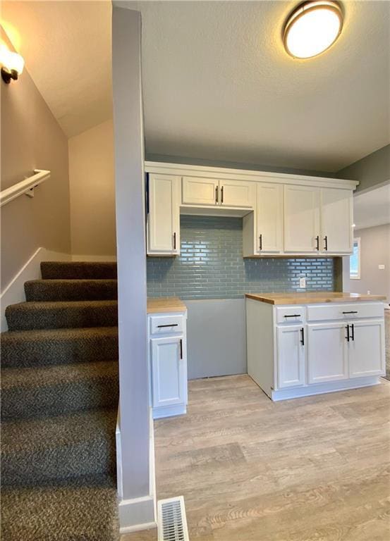 3046 N 27th St, Kansas City, KS 66104 - kitchen featuring light wood-type flooring, white cabinetry, decorative backsplash, butcher block counters, and vaulted ceiling