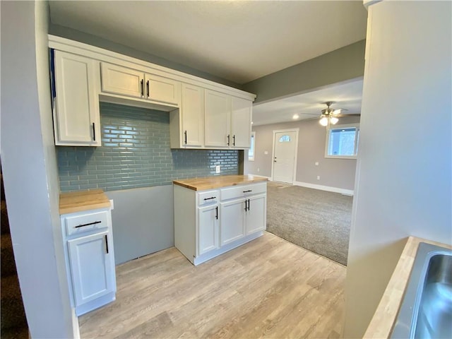 3046 N 27th St, Kansas City, KS 66104 - kitchen featuring wood counters, a ceiling fan, decorative backsplash, white cabinetry, and light wood-style flooring