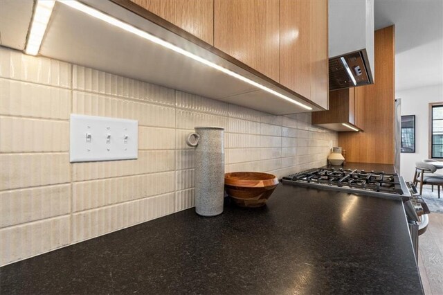 529 E 19th St, Kansas City, MO 64108 - kitchen view of dark countertops, wall chimney range hood, and decorative backsplash