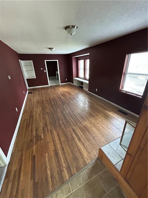 907 S Cedar Ave, Independence, MO 64052 - unfurnished living room featuring a textured ceiling and wood finished floors