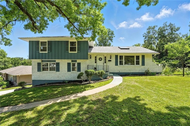 2903 E 107th Ter, Kansas City, MO 64137 - split level home with board and batten siding, roof mounted solar panels, brick siding, and a front lawn