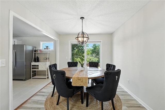 2903 E 107th Ter, Kansas City, MO 64137 - dining area with light wood finished floors, a chandelier, and a textured ceiling