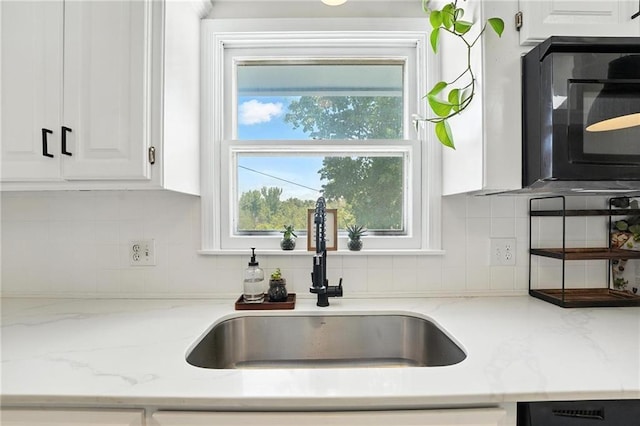 2903 E 107th Ter, Kansas City, MO 64137 - kitchen with black microwave, white cabinets, tasteful backsplash, and light stone counters