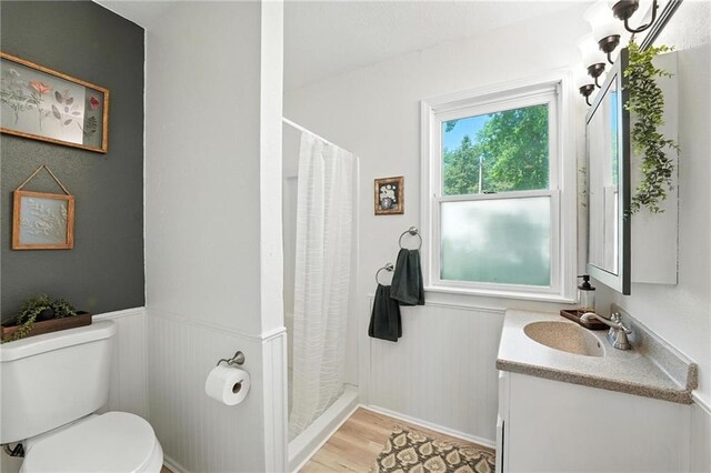 2903 E 107th Ter, Kansas City, MO 64137 - bathroom featuring vanity, wainscoting, wood finished floors, and curtained shower