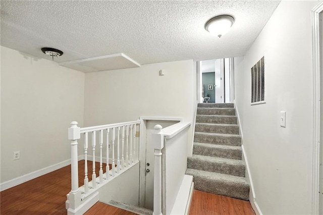 2903 E 107th Ter, Kansas City, MO 64137 - staircase featuring a textured ceiling and wood finished floors