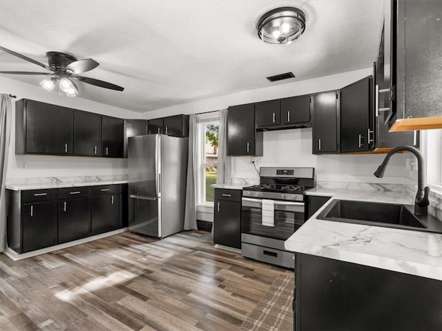 915 N 24th St, Saint Joseph, MO 64506 - kitchen featuring appliances with stainless steel finishes, dark cabinetry, a ceiling fan, and light wood-style floors